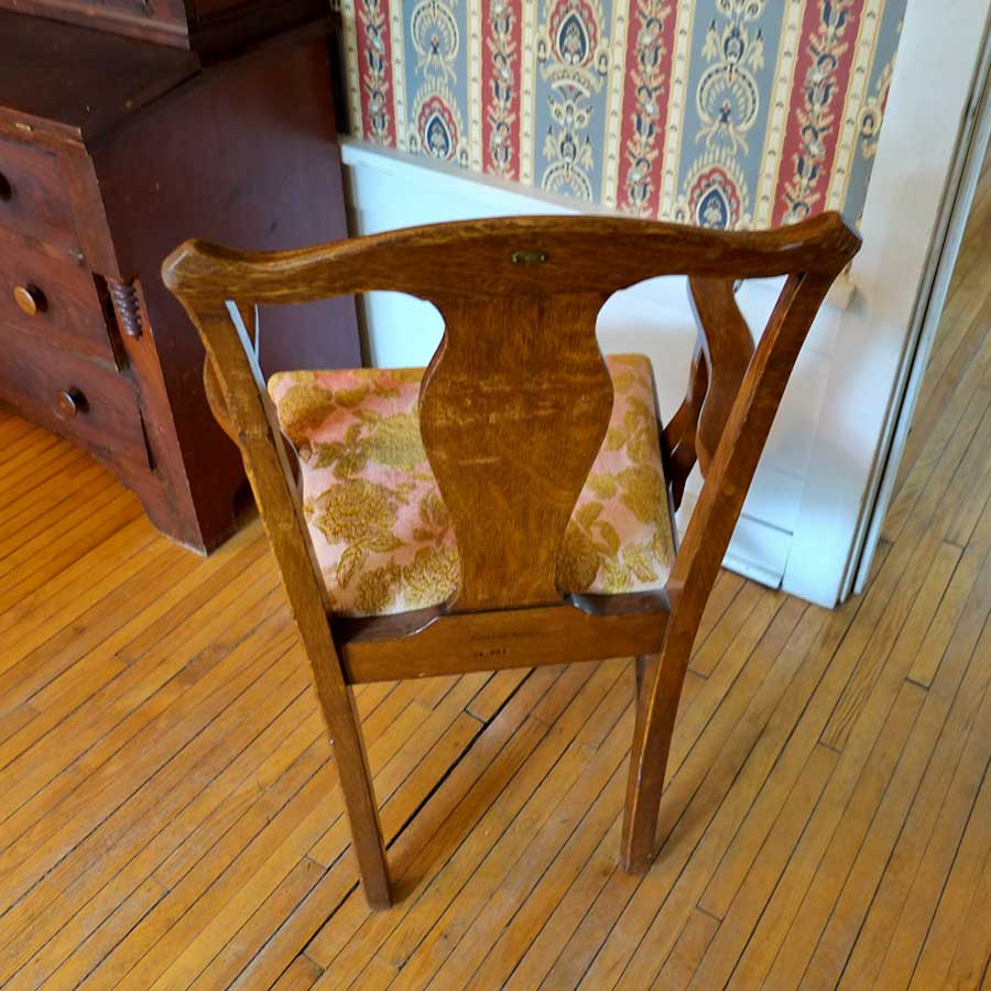 photo showing stamped MINN mark on 1087 Armchair, purchased by Cass Gilbert for the 1905 Minnesota State Capitol, carved wood with fabric cushion seat cover