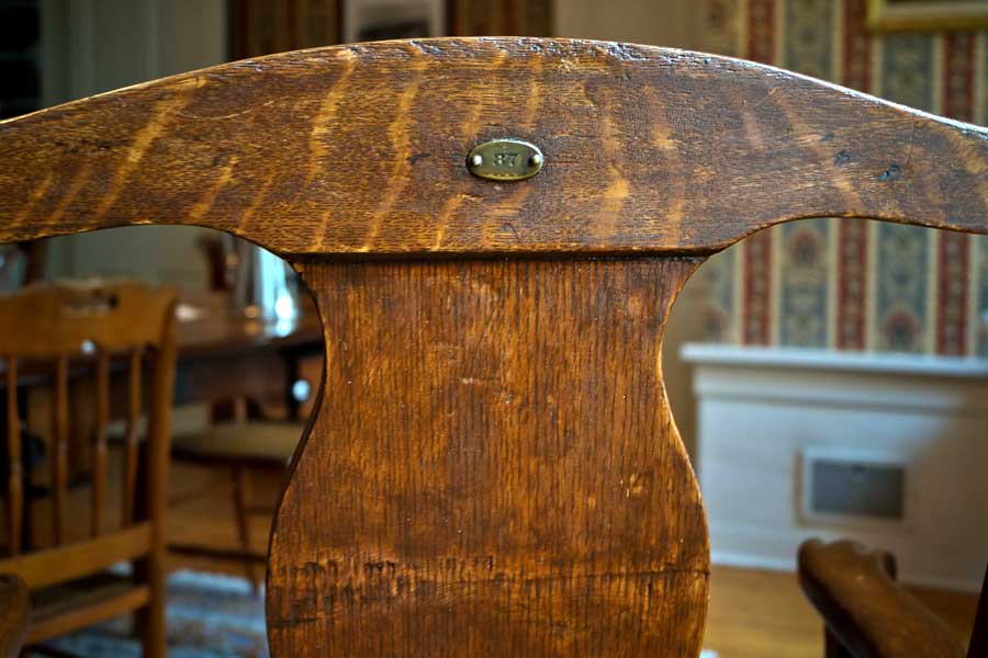 photo showing stamped MINN mark on 1087 Armchair, purchased by Cass Gilbert for the 1905 Minnesota State Capitol, carved wood with fabric cushion seat cover