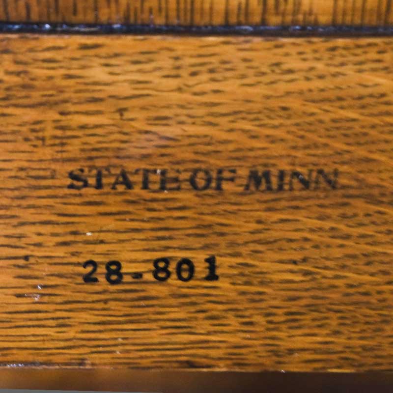 photo showing stamped MINN mark on 1087 Armchair, purchased by Cass Gilbert for the 1905 Minnesota State Capitol, carved wood with fabric cushion seat cove